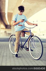 people, communication, technology, leisure and lifestyle - hipster man with smartphone and earphones on fixed gear bike listening to music on city street. man with smartphone and earphones on bicycle