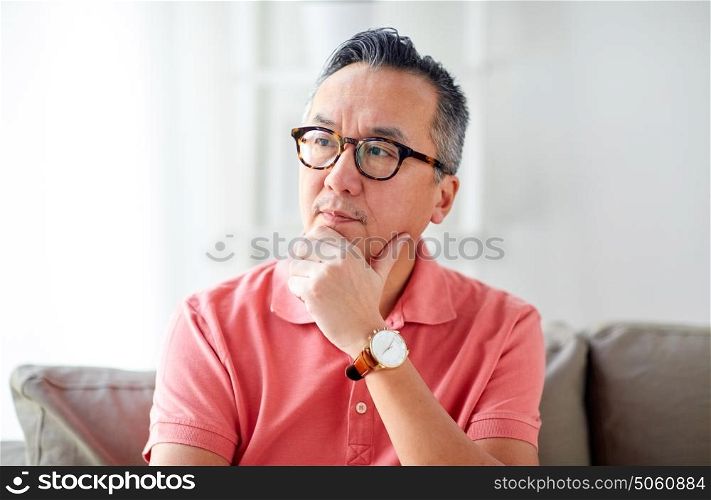 people concept - asian man thinking at home. asian man thinking at home