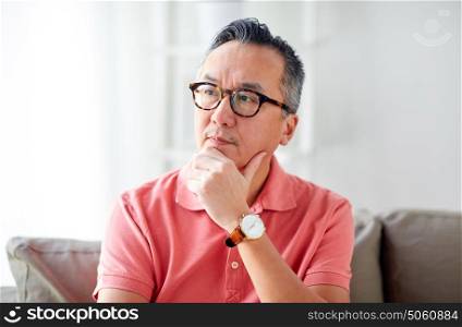 people concept - asian man thinking at home. asian man thinking at home