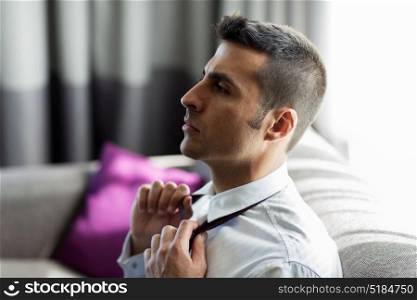 people concept - businessman taking off his tie at hotel room. businessman taking off his tie at hotel room