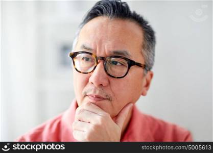 people concept - close up of asian man thinking at home. close up of asian man thinking at home