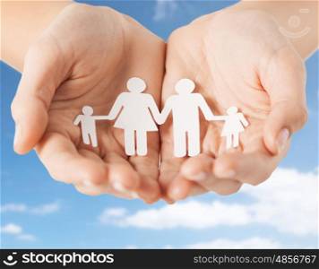 people concept - close up of female hands holding paper family pictogram over blue sky and clouds background. close up of hands holding paper family pictogram