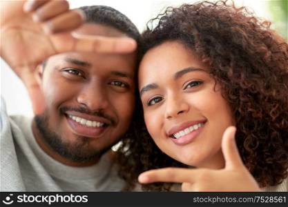 people concept - happy african american couple making selfie or viewfinder viewfinder gesture at home. happy couple making selfie gesture at home