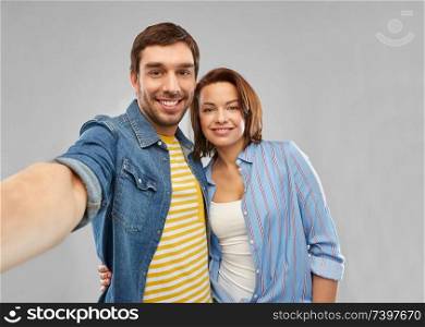 people concept - happy couple hugging and taking selfie over grey background. happy couple taking selfie over grey background