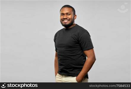 people concept - happy smiling young african american man in black t-shirt over grey background. smiling african american man in black t-shirt