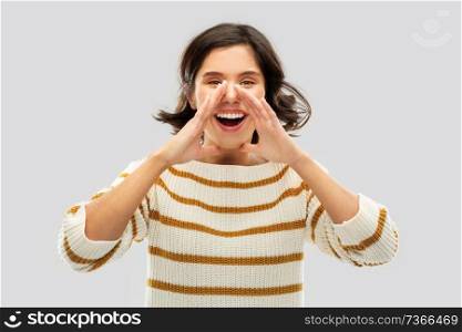 people concept - happy smiling young woman in striped pullover calling someone over grey background. happy woman in striped pullover calling someone