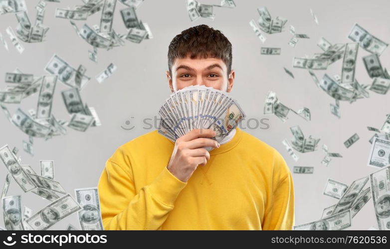 people concept - happy young man in yellow sweatshirt with money over grey background. happy young man in yellow sweatshirt with money