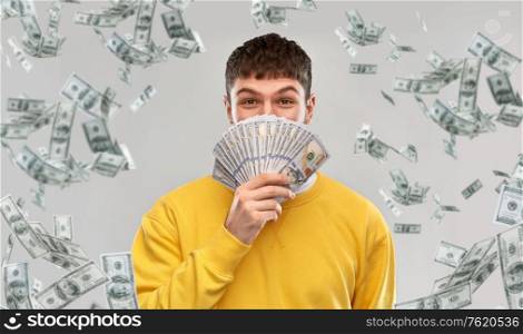 people concept - happy young man in yellow sweatshirt with money over grey background. happy young man in yellow sweatshirt with money