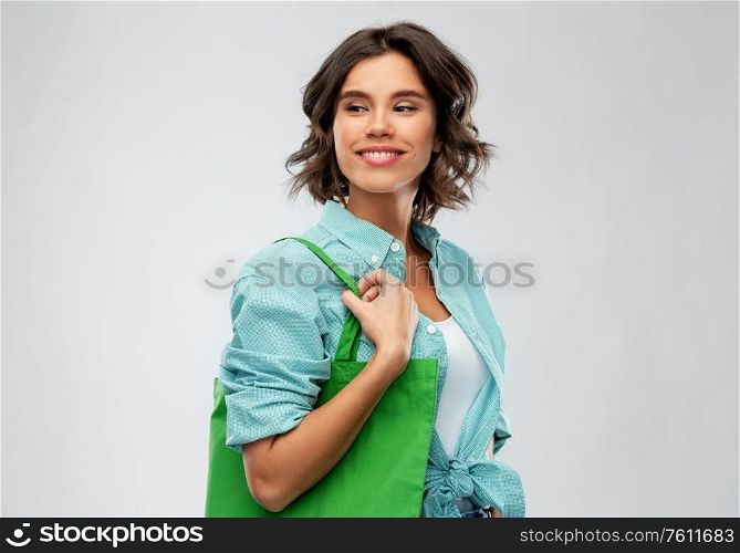 people concept - portrait of happy smiling young woman in turquoise shirt with green reusable canvas bag for food shopping on grey background. woman with reusable canvas bag for food shopping
