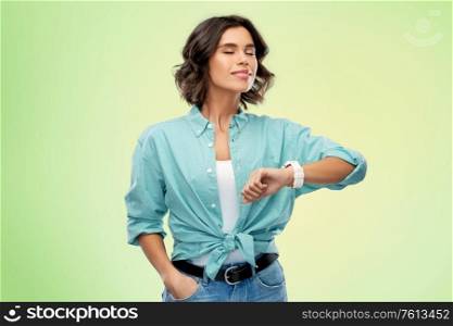 people concept - portrait of happy smiling young woman in turquoise shirt with smart watch breathing over green background. smiling young woman with smart watch breathing