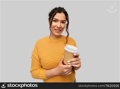 people concept - portrait of happy smiling young woman with pierced nose holding takeaway coffee cup over grey background. smiling woman with pierced nose holding coffee cup