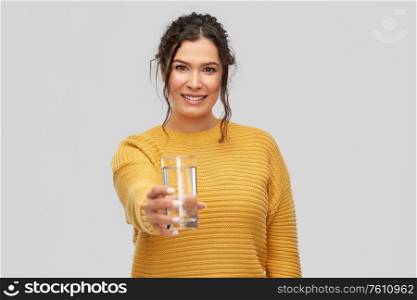 people concept - portrait of happy smiling young woman with water in glass over grey background. smiling young woman with water in glass
