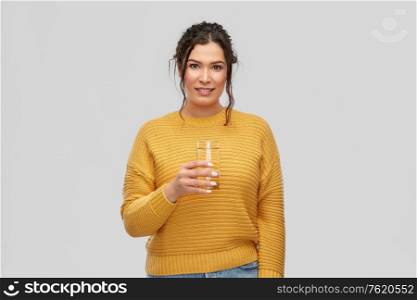 people concept - portrait of happy smiling young woman with water in glass over grey background. smiling young woman with water in glass