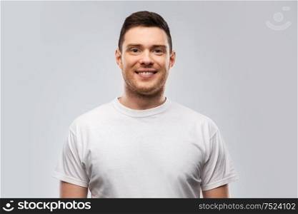 people concept - portrait of smiling young man in white t-shirt over grey background. portrait of smiling young man in white t-shirt