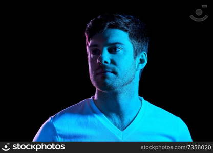 people concept - portrait of young man in t-shirt over ultra violet neon lights in dark room. portrait of man over neon lights in dark room