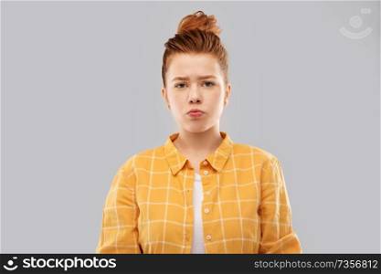 people concept - sad red haired teenage girl in checkered shirt pouting over grey background. sad red haired teenage girl in shirt pouting
