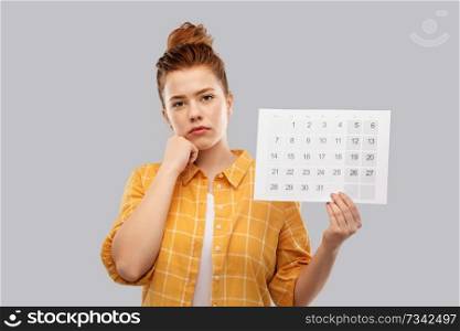 people concept - sad red haired teenage girl in checkered shirt with calendar sheet over grey background. sad red haired teenage girl with calendar sheet