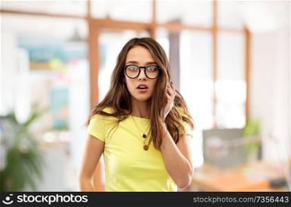 people concept - scared young woman or teenage girl in yellow t-shirt and glasses over office background. scared young woman or teenage girl in glasses
