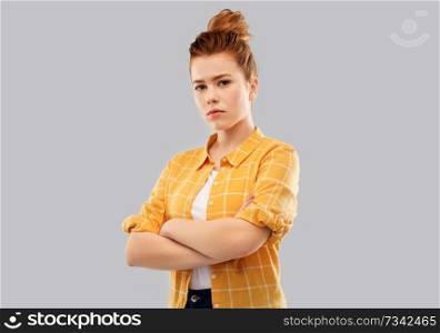 people concept - serious red haired teenage girl in checkered shirt with crossed arms over grey background. serious red haired teenage girl with crossed arms