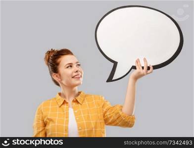 people concept - smiling red haired teenage girl in checkered shirt holding blank speech bubble over grey background. red haired teenage girl holding speech bubble