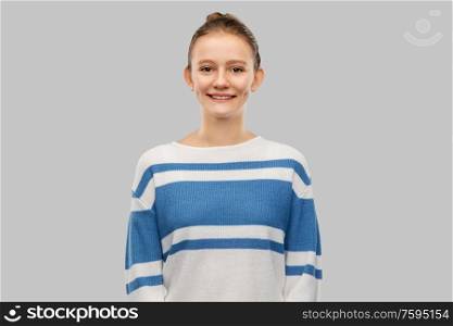 people concept - smiling teenage girl in pullover over grey background. smiling teenage girl in pullover