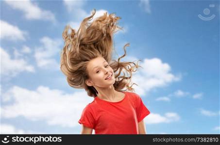 people concept - smiling teenage girl in red t-shirt with long hair waving over blue sky and clouds background. smiling teenage girl in red with long wavy hair
