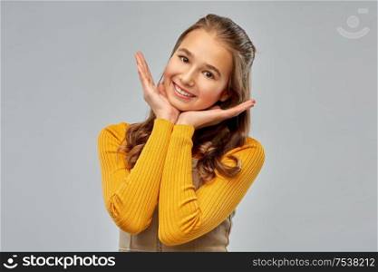 people concept - smiling teenage girl over grey background. smiling teenage girl over grey background