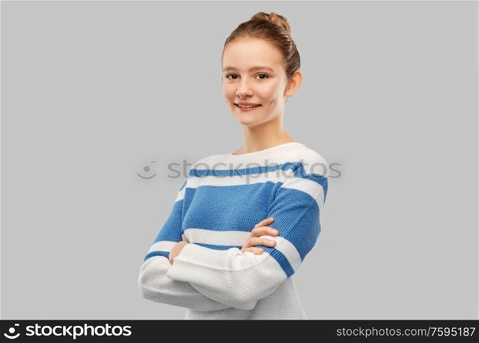people concept - smiling teenage girl with crossed arms in pullover over grey background. smiling teenage girl with crossed arms in pullover