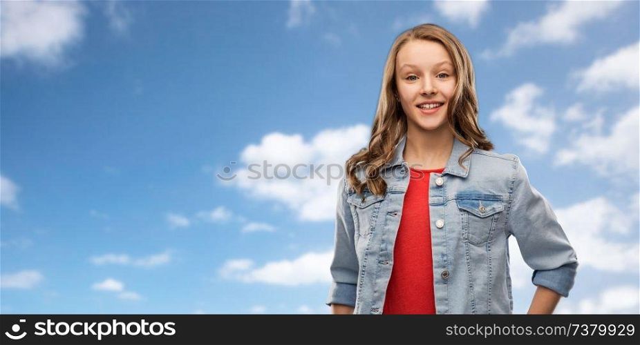 people concept - smiling teenage girl with long hair in denim jacket over blue sky and clouds background. smiling teenage girl in denim jacket over sky