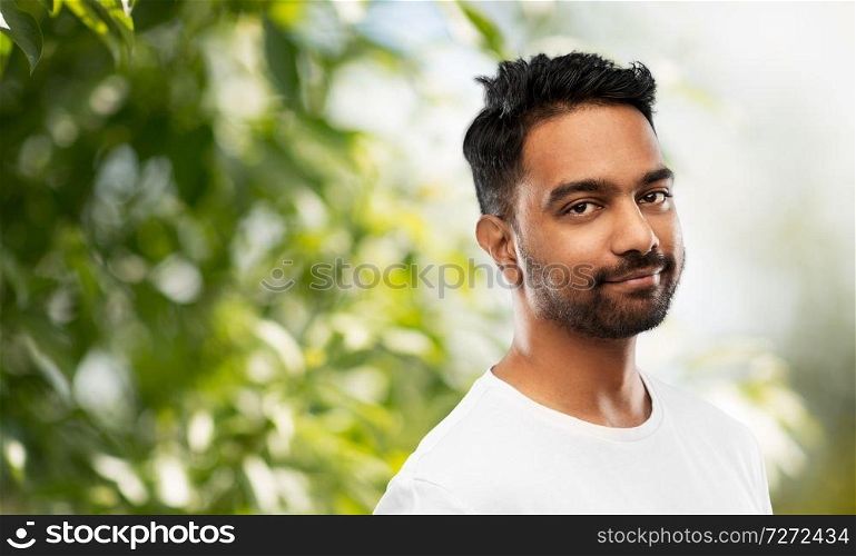 people concept - smiling young indian man over green natural background. smiling young indian man over gray background