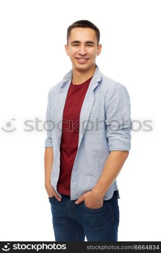 people concept - smiling young man holding hands in pockets over white background. smiling young man holding hands in pockets