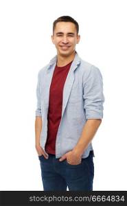 people concept - smiling young man holding hands in pockets over white background. smiling young man holding hands in pockets
