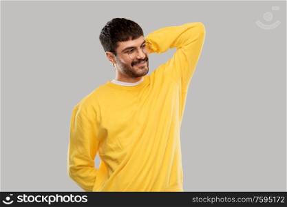 people concept - smiling young man in glasses and yellow sweatshirt over grey background. smiling young man in glasses and yellow sweatshirt