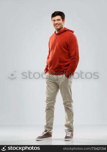 people concept - smiling young man in red hoodie over grey background. young man in red hoodie over grey background