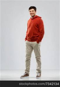 people concept - smiling young man in red hoodie over grey background. young man in red hoodie over grey background