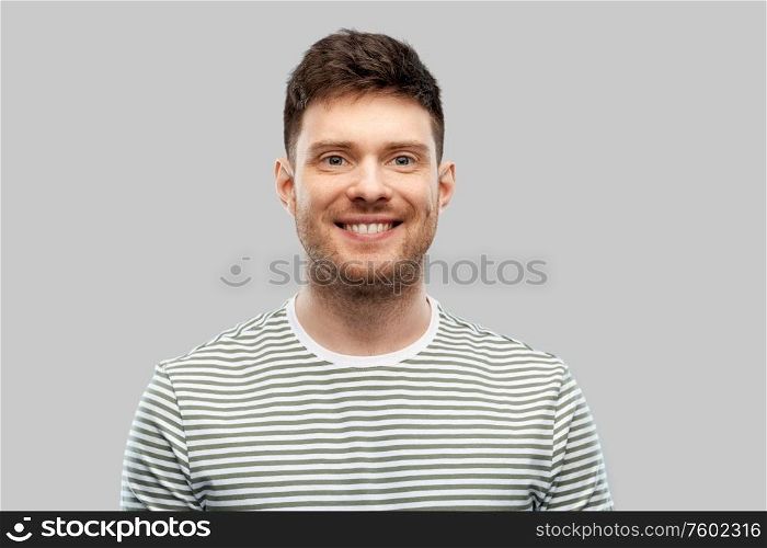 people concept - smiling young man in striped t-shirt over grey background. smiling young man in striped t-shirt