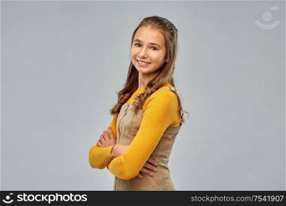 people concept - smiling young teenage girl with crossed arms over grey background. smiling young teenage girl with crossed arms