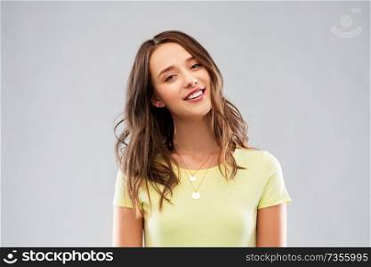 people concept - smiling young woman or teenage girl in blank yellow t-shirt over grey background. young woman or teenage girl in yellow t-shirt