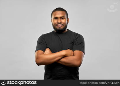 people concept - young african american man in black t-shirt with crossed arms over grey background. african american man with crossed arms