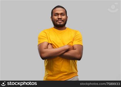 people concept - young african american man in yellow t-shirt with crossed arms over grey background. african american man with crossed arms