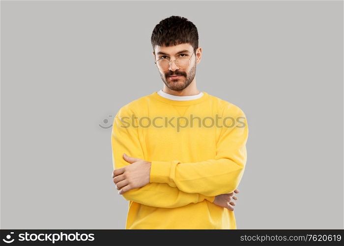 people concept - young man in glasses and yellow sweatshirt over grey background. young man in glasses and yellow sweatshirt