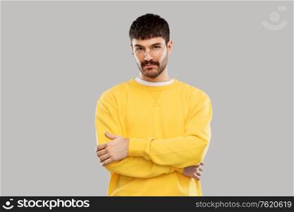 people concept - young man in glasses and yellow sweatshirt over grey background. young man in glasses and yellow sweatshirt