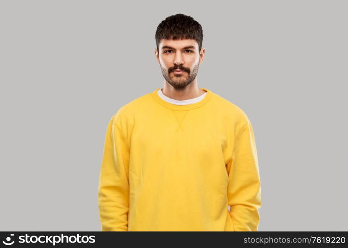 people concept - young man in yellow sweatshirt over grey background. young man in yellow sweatshirt