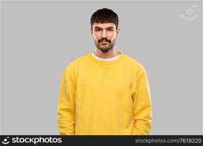people concept - young man in yellow sweatshirt over grey background. young man in yellow sweatshirt
