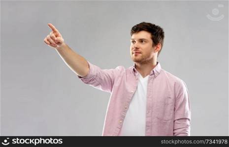 people concept - young man showing something over grey background. young man showing something