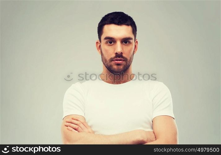 people concept - young man with crossed arms over gray background. young man with crossed arms over gray background