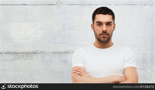 people concept - young man with crossed arms over gray stone wall background. young man with crossed arms over gray background