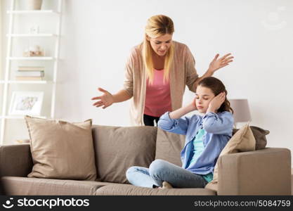 people, conflict and family concept - girl covering ears to not hear angry mother at home. girl closing ears to not hear angry mother at home. girl closing ears to not hear angry mother at home