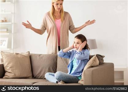 people, conflict and family concept - girl covering ears to not hear angry mother at home. girl closing ears to not hear angry mother at home