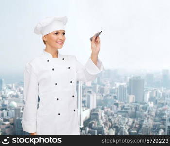 people, cooking and advertisement concept - smiling female chef, cook or baker with marker writing something on air over city background